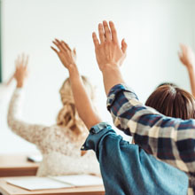 Alunos com as mãos levantadas em uma sala de aula